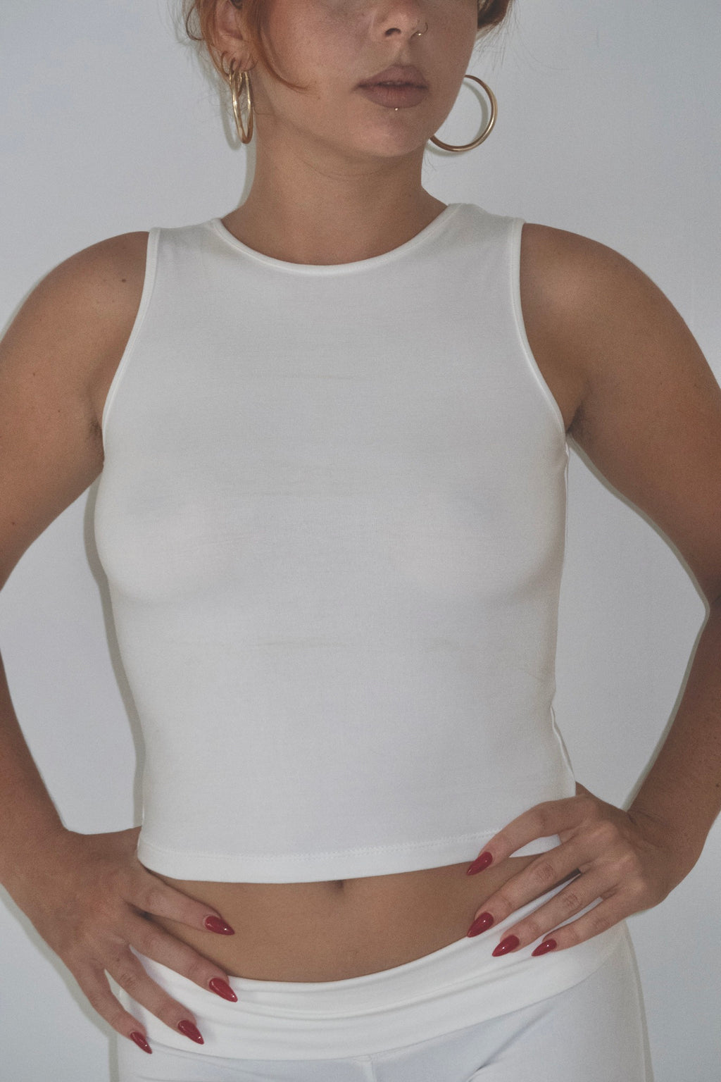 Person wearing a white sleeveless top against a plain background